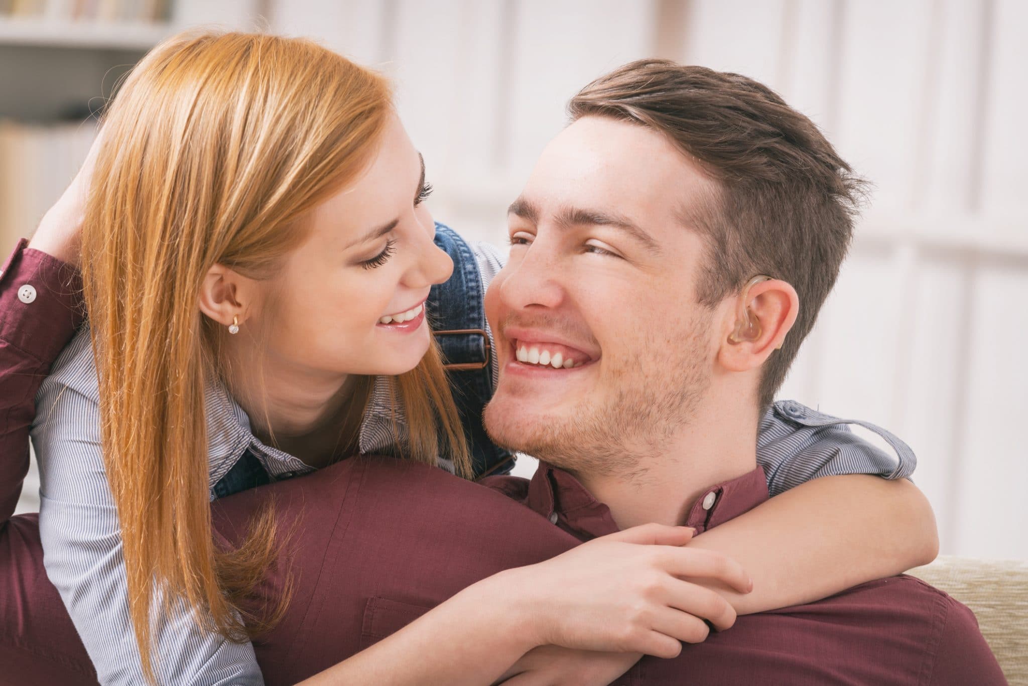 A woman hugging a man wearing hearing aids.