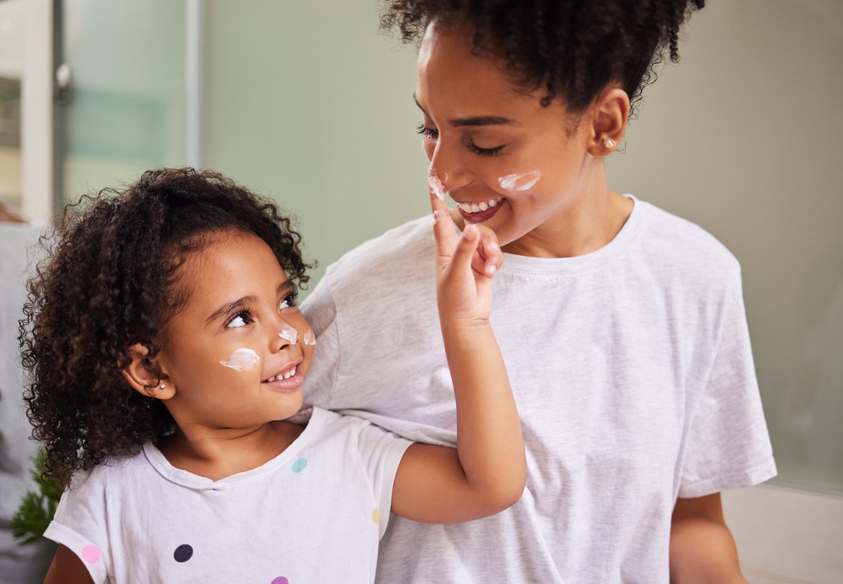 mom and daughter putting on sunscreen  