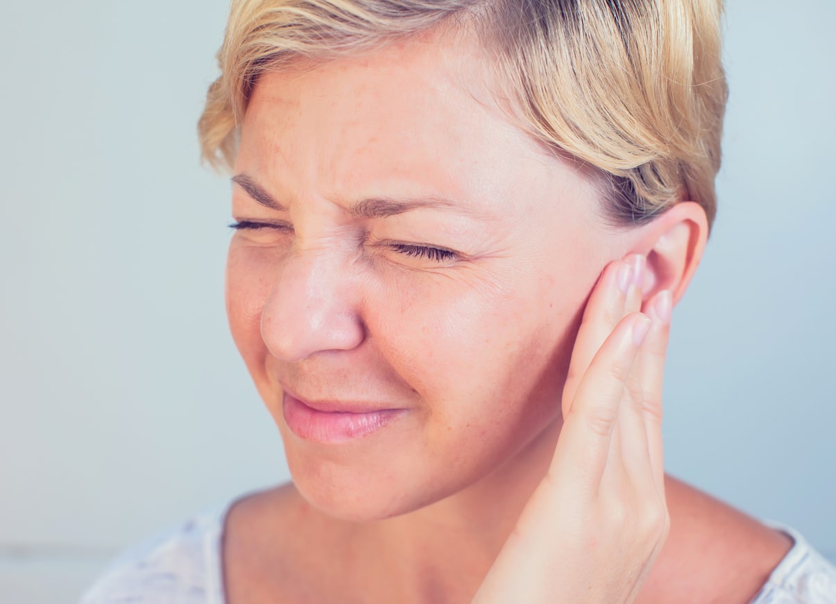 Woman with tinnitus holding her ear.