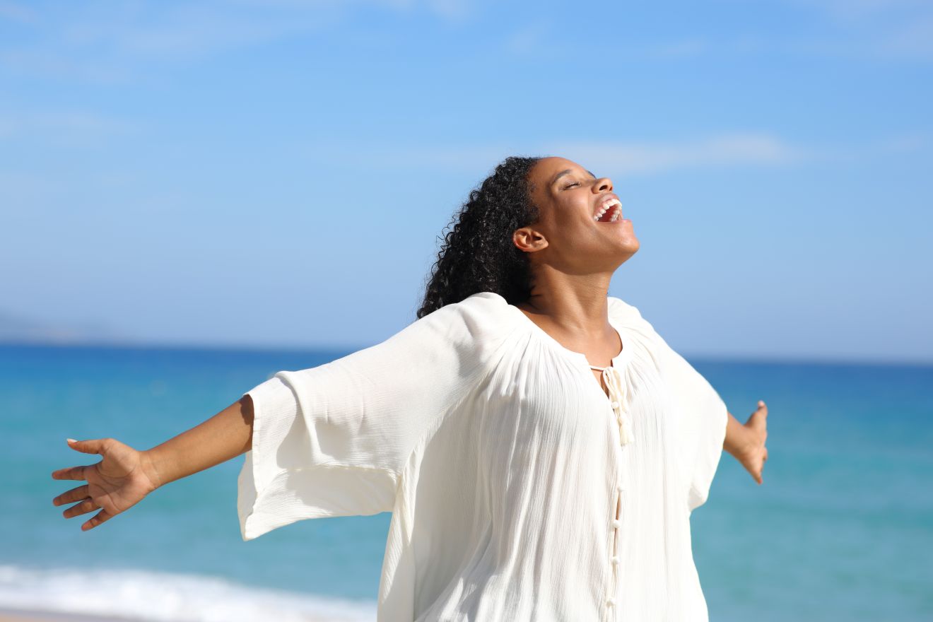 woman celebrating on beach after dizziness treatment.